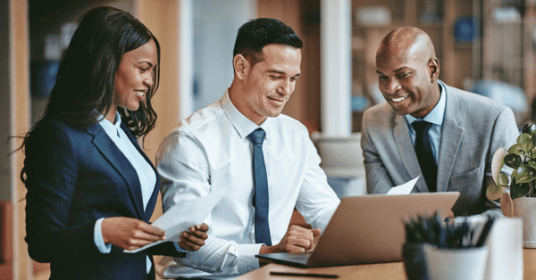 business people dressed smartly gather round a laptop