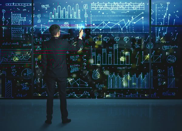 Man calculating on a glass whiteboard